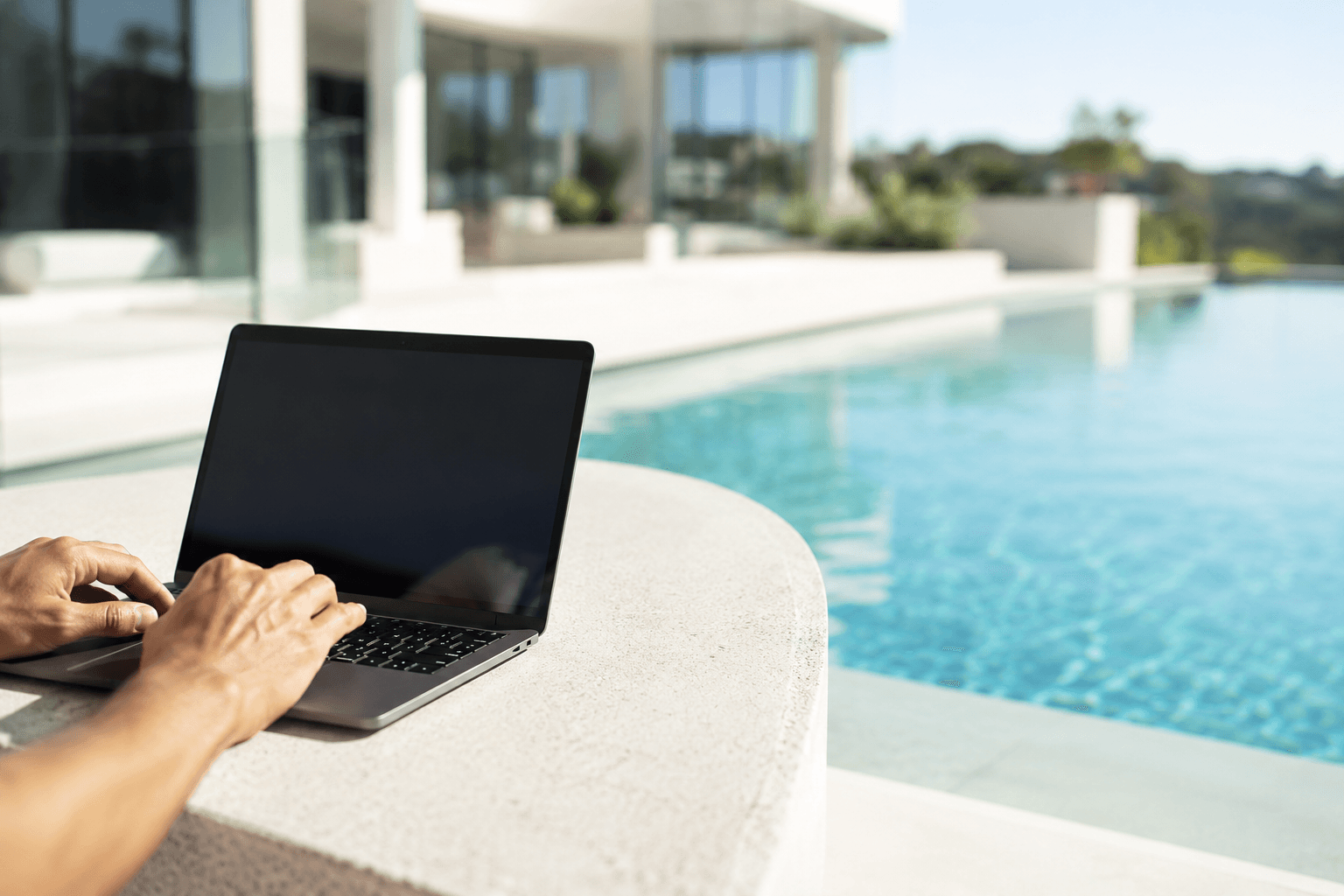 Laptop displaying performance analytics on a concrete ledge beside a premium pool