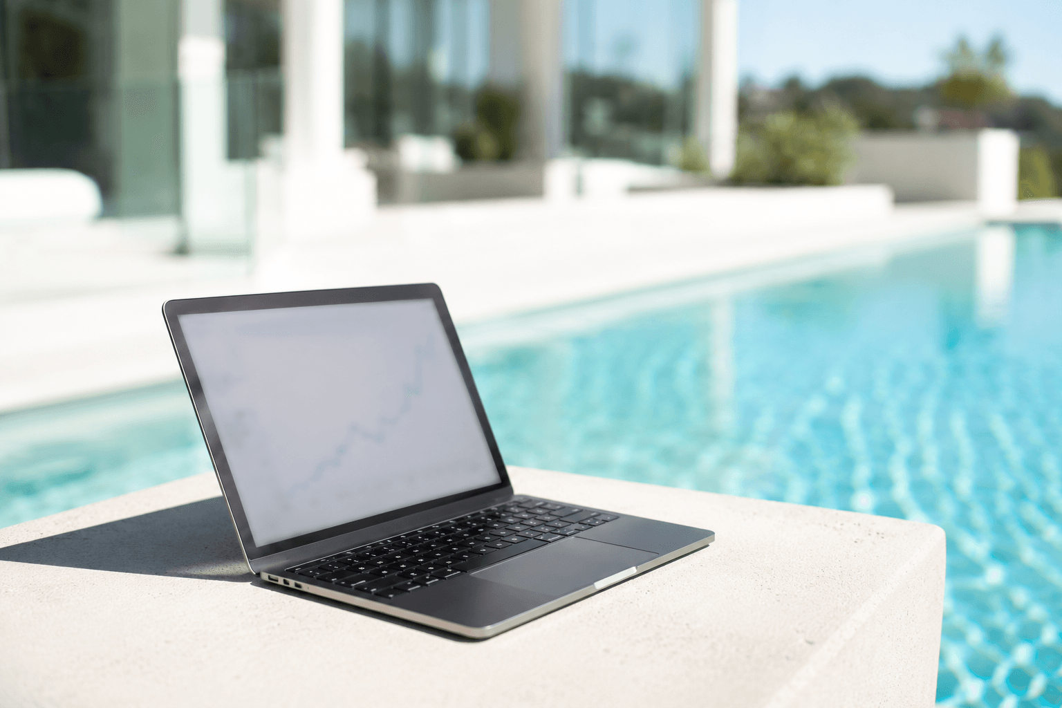 Laptop with analytics dashboard open on a poolside terrace at a luxury property